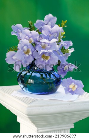 Bunch of Blue Allamanda exotic tropical flowers in a vase and a cup of tea