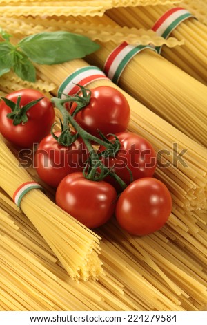 Italian cuisine: Spaghetti bunch wrapped by Italian flag colors ribbon,  cherry tomatoes and basil l still life