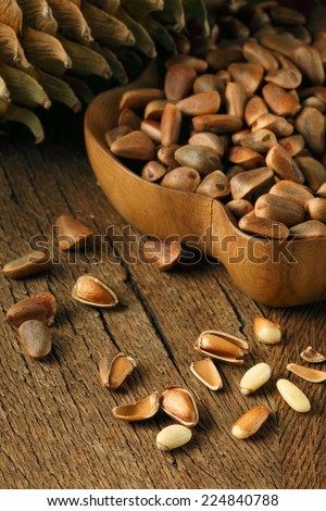 Pine nuts/ cedar nuts in shells and pine cone on wooden background