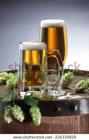 Beer glass and hops on beer barrel still life