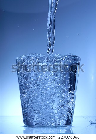 Pouring water into a glass isolated on white background