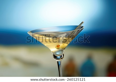 Martini glass with olive, sea on the background