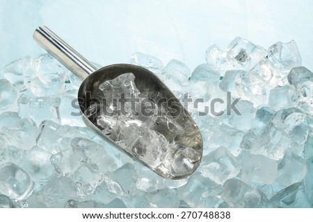 Ice cubes in a metal scoop on ice cubes background