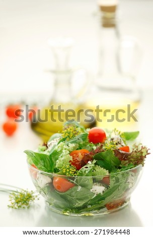 Mixed green salad with  Lettuce, Spinach, Feta  cheese, Lollo rosso, Lollo Bionda  and fresh Cherry Tomatoes  in a  clear glass bowl on white background