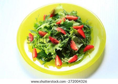 Mixed green salad with  Rocket leaves, Spinach, Basil, flower petals  and fresh strawberries in a   glass plate