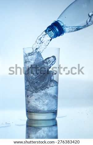 Pouring water. Glass of water with ice cubes isolated on white background