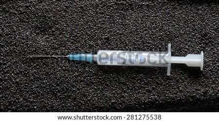 Syringe on black poppy flower seeds background