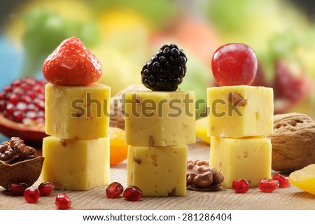 Hard cheese cubes served on sticks with walnuts, blackberries, strawberries, pomegranate and grapes