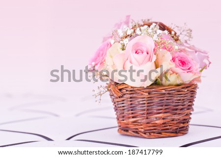 pink roses in brown basket of pink background