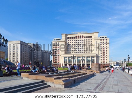 MOSCOW - MAY 12: People having a rest on benches on Manezh Square on May 12, 2014 in Moscow. There are State Duma building (left) and Four Seasons Hotel Moscow on background.