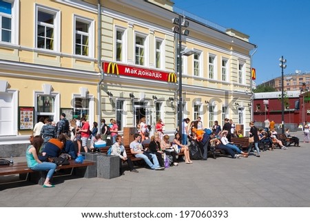 MOSCOW - MAY 31: People sitting near McDonald\'s restaurant building at Tolmachesvsky street on May 31, 2014 in Moscow.