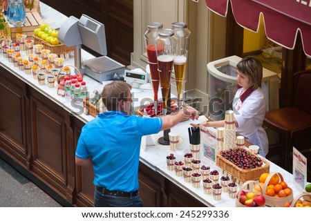 MOSCOW - JULY 29: The buyer pays the money to the seller of fruit and soft drinks in the GUM store on July 29, 2014 in Moscow.