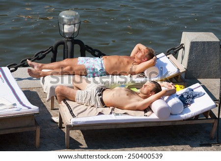 MOSCOW - JULY 31: Two men lying on couches and sunbathing at Olive Beach in Gorky Park on July 31, 2014 in Moscow. Olive Beach is located on the bank of Moskva River.