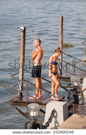 MOSCOW - JULY 31: Young man and woman taking a shower at Olive Beach in Gorky Park on July 31, 2014 in Moscow. Olive Beach is located on the bank of Moskva River.