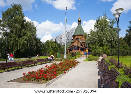 MOSCOW - AUGUST 2: People resting on benches near a wooden cathedral in Heritage Village Park in Bibirevo district on August 2, 2013 in Moscow. Bibirevo is district of North-Eastern part of Moscow.