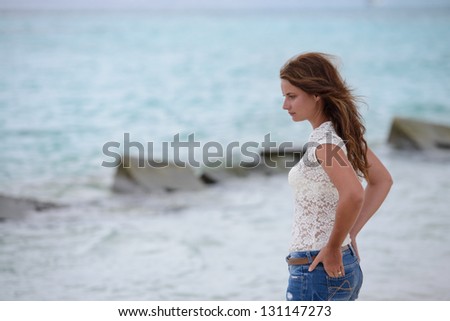 Young woman sitting on the beach, watching the sea