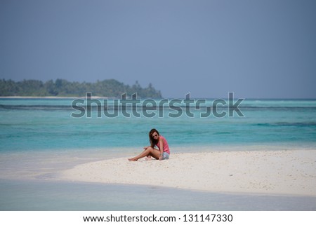 A young woman dreaming on a beach near the turquoise water of Maldive islands