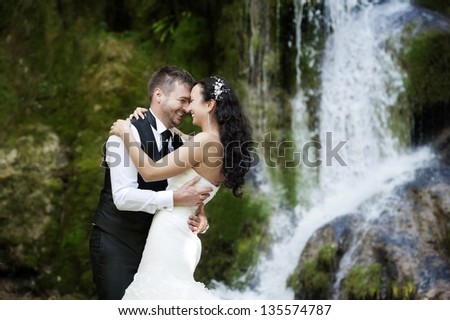 Lovely smiling couple at their wedding photo session near a waterfall