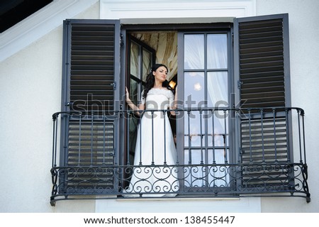 Delicate bride dreaming and looking on the window in her wedding day