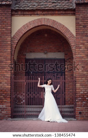 Happy and delicate bride sitting in her wedding day, in front of the church