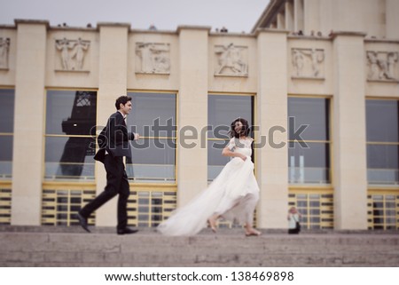 Bride and groom running on their wedding day in Paris, in front of the Eiffel tour