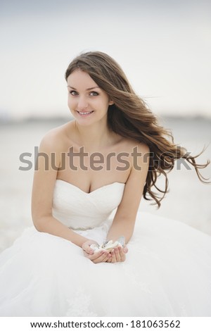 Bride at a photo session near the sea, holding some shells in her hand