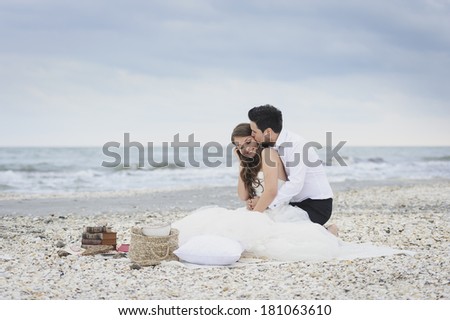 Bride and groom kissing at a photo session near the sea, surrounded by shells