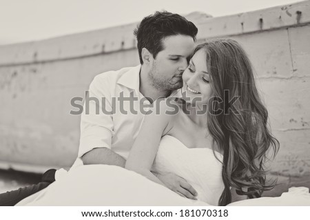 Bride and groom kissing at a photo session, near a boat close to the sea