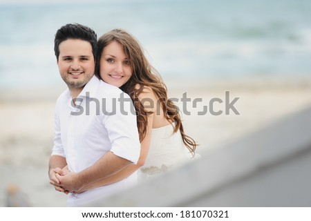 Bride and groom smiling at a photo session, near a boat close to the sea