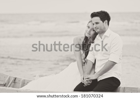 Bride and groom dreaming, at a photo session, near a boat close to the sea
