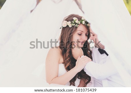 Bride and groom sitting in a tent at a photo session in the nature, looking at each other