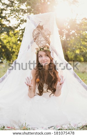 Beautiful bride sitting in a tent photo session in the nature