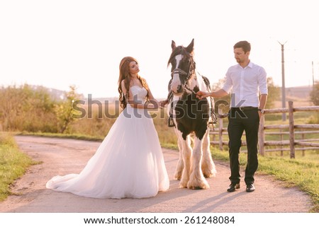 Bride and groom having a romantic moment on their wedding day, looking at their horse