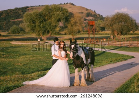 Bride and groom having a romantic moment on their wedding day, looking at a horse