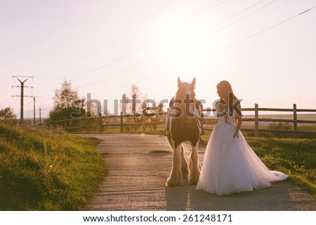 Stunning and beautiful bride dreaming near her horse in her wedding day