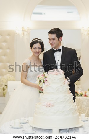 Beautiful couple posing on their wedding day with the wedding cake