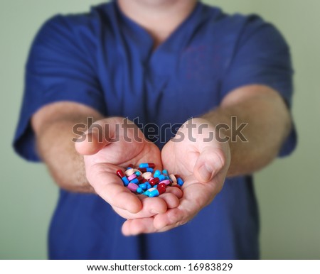 Male doctor or nurse hand holding an assortment of pills
