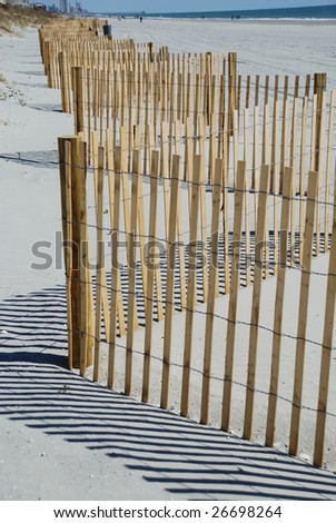 Picket fence on beach with strong shadows