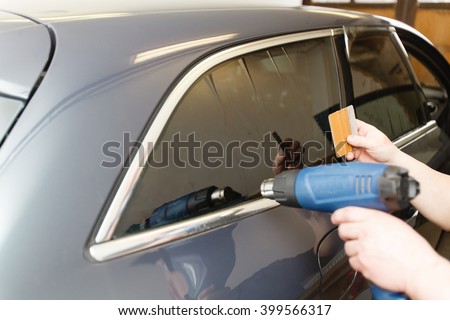 Applying tinting foil on a car window in a garage