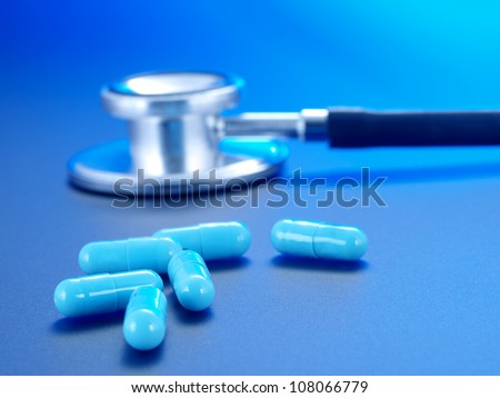Stethoscope and blue pills on a blue background.