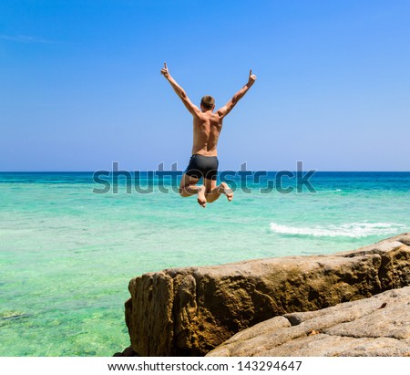 The happy young man jumping in the sea
