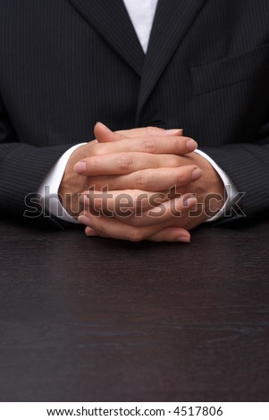 Businesswoman at contract table. Hands folded.