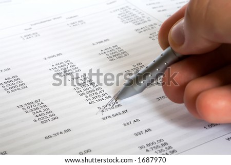 checking balance - man's hand holding pen and checking spreadsheet