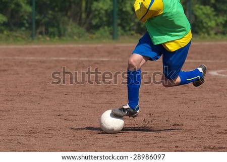 soccer player dribbling on a cinder pitch