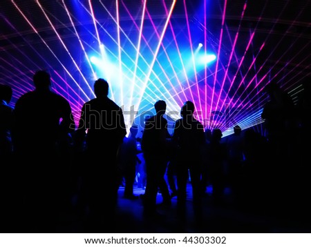 stock photo Dancing people in a disco in front of blue laser lights