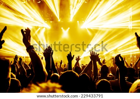 silhouettes of concert crowd in front of bright stage lights
