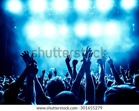 silhouettes of concert crowd in front of bright stage lights - a small depth of field signifies that the focused area is narrow