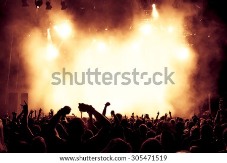 silhouettes of concert crowd in front of bright stage lights - a small depth of field signifies that the focused area is narrow
