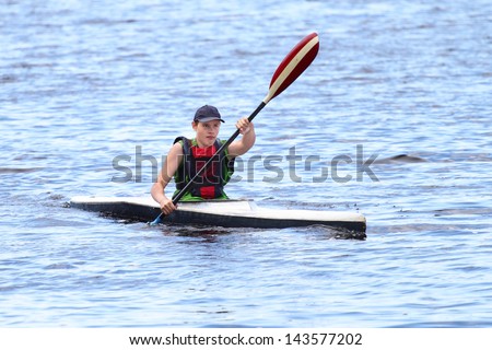 Boy in sport kayak paddles on the water