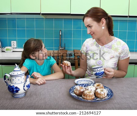 Mother offers daughter cake at teatime in kitchen